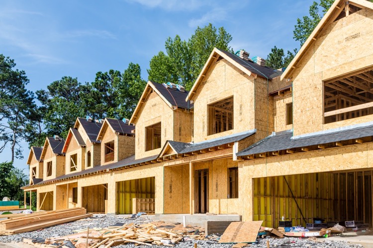 row home structure under cloudy blue sky huge pile of debis in front